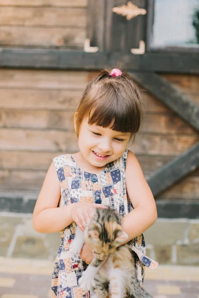 Fröhliches kleines Mädchen mit einer Katze im Arm — Stockfoto