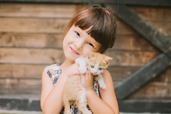 Веселая маленькая девочка с котом на руках — стоковое фото