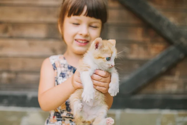 Menina alegre segurando um gato em seus braços — Fotografia de Stock