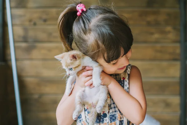 Joyeuse petite fille tenant un chat effrayé dans les mains — Photo