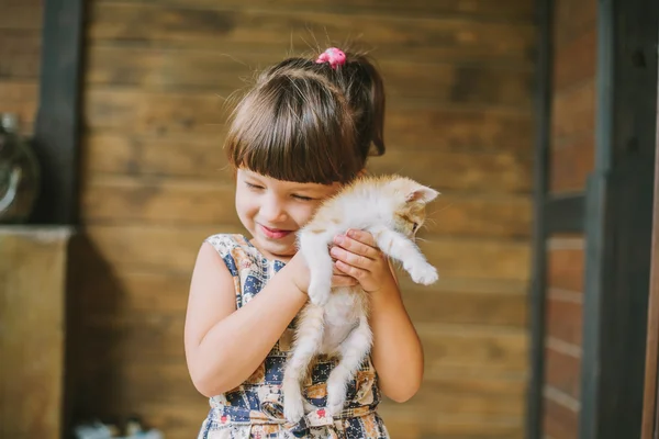 Fröhliches kleines Mädchen mit einer Katze im Arm — Stockfoto