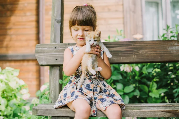 Menina brincando com gatinhos em um banco — Fotografia de Stock