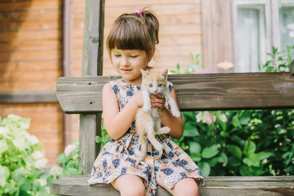 bir bankta yavru kedi ile oynarken kız