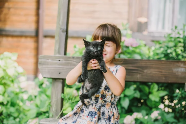 Menina brincando com gatinhos em um banco — Fotografia de Stock