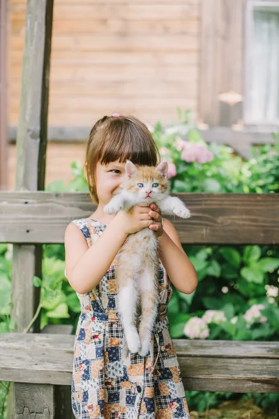 bir bankta yavru kedi ile oynarken kız