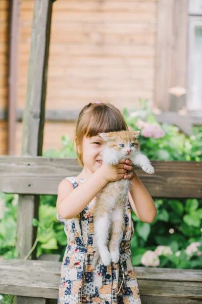 Mädchen spielt mit Kätzchen auf einer Bank — Stockfoto