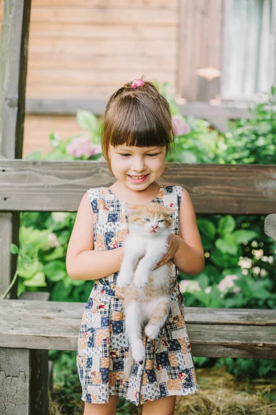 bir bankta yavru kedi ile oynarken kız