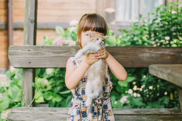 Menina brincando com gatinhos em um banco — Fotografia de Stock