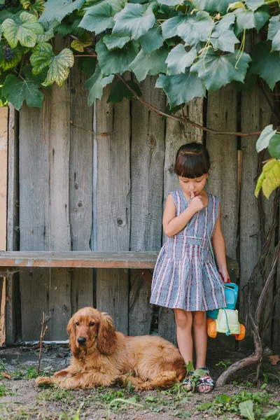 Menina do campo com seu cão sob a videira. fundo de madeira — Fotografia de Stock