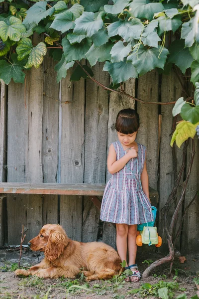 Menina do campo com seu cão sob a videira. fundo de madeira — Fotografia de Stock