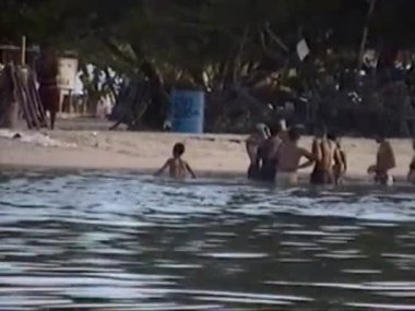 İnsanlar sahilde ve teknelerde eğleniyor. Carenero, Miranda State, Venezuela, 1 Ocak 2001. 8 mm 'lik video. Yazı.