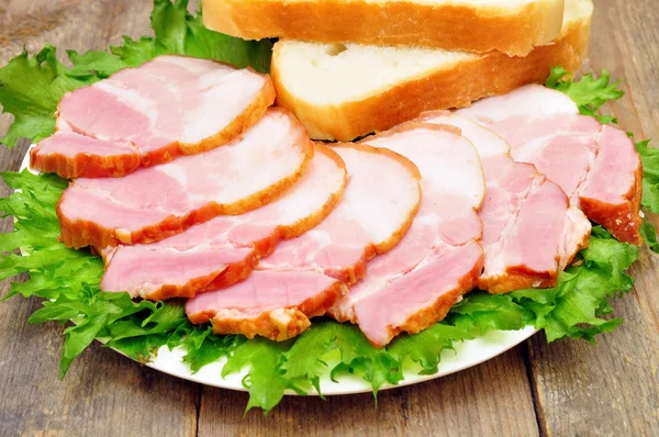 Sliced bacon on a plate with bread — Stock Photo, Image