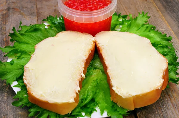 Sanduíches com manteiga em uma chapa e um banco com caviar de salmão — Fotografia de Stock
