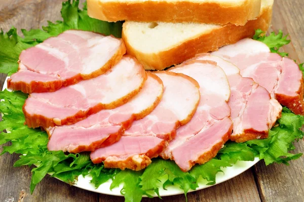 Sliced bacon on a plate with bread — Stock Photo, Image