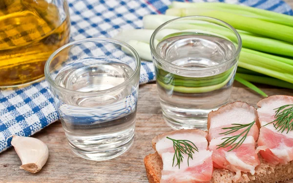 Et glass vodka, løk og baconsmørbrød – stockfoto