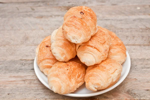 Croissants in a saucer on a wooden table — Stock Photo, Image