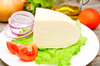 Bir kase sebze ile ahşap bir masa üzerinde yumuşak keçi peyniri