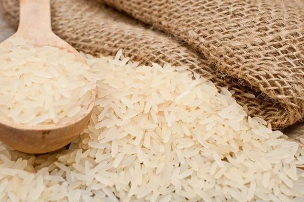 Rice from the bag and wooden spoon — Stock Photo, Image