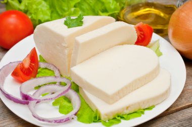 Bir kase sebze ile ahşap bir masa üzerinde yumuşak keçi peyniri
