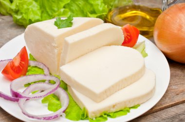 Bir kase sebze ile ahşap bir masa üzerinde yumuşak keçi peyniri