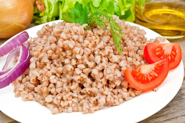 Buckwheat groats in a bowl on a wooden table — Stock Photo, Image