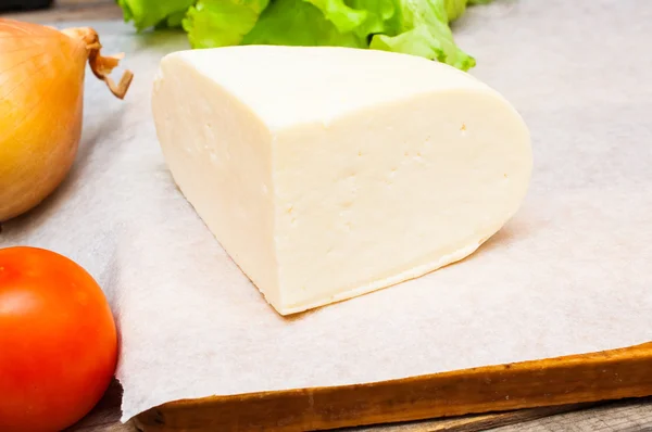 Мягкий козий сыр в миске на деревянном столе с овощами — стоковое фото