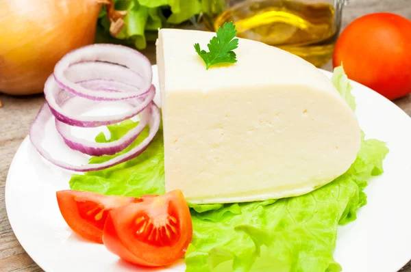 Bir kase sebze ile ahşap bir masa üzerinde yumuşak keçi peyniri 