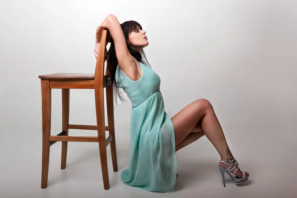 Young woman posing with chair in studio — Stock Photo, Image