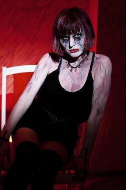 Vampir kız kırmızı üzerinde oturan poz