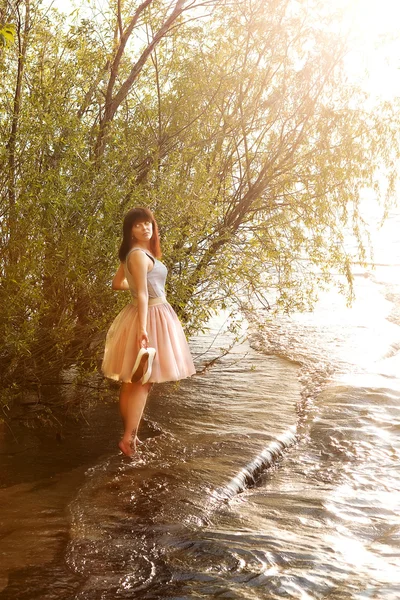 Menina na margem do rio com sapatos na mão — Fotografia de Stock