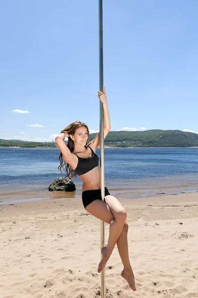 Curly brunette on sea beach with pole — Stock Photo, Image