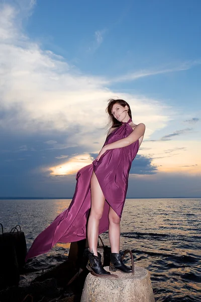Brünette im Kleid am Ufer des Flusses Sonnenuntergang — Stockfoto