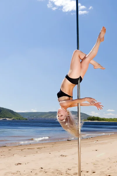 Danseuse blonde exécutant une danse acrobatique sur pôle — Photo