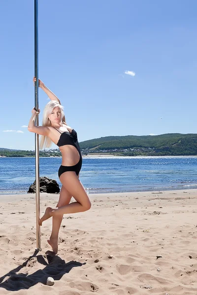 Blonde with pole for poledance in black bathing suit — Stock Photo, Image