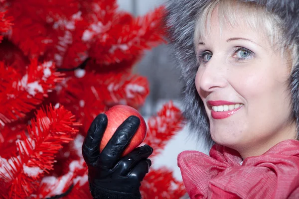 Beautiful woman in winter fur hat on a red background Christmas tree — Stock Photo, Image
