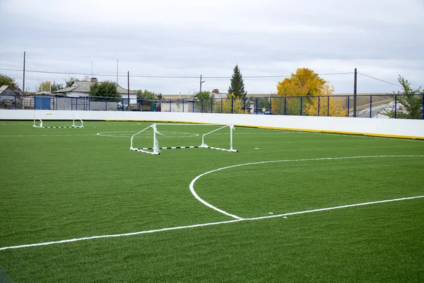 Boş futbol ile yeşil çim alan ve köyün geçidine devrik