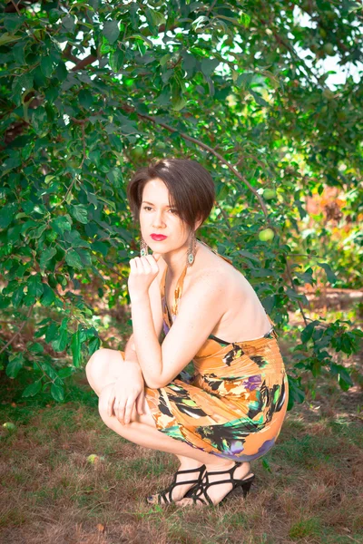 Beautiful girl in dress sitting in the garden — Stock Photo, Image