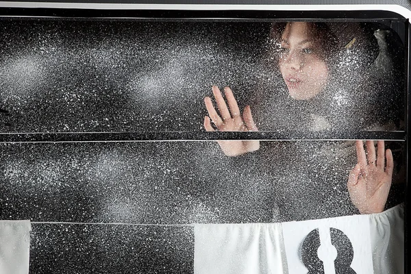 Vacker flicka över snön täckte fönster — Stockfoto