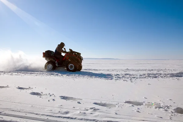 Hombre montar en quad bicicleta en el campo de invierno nevado Fotos de stock libres de derechos