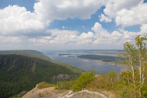 Fragment of rock against mountains with trees horizontally — Stock Photo, Image