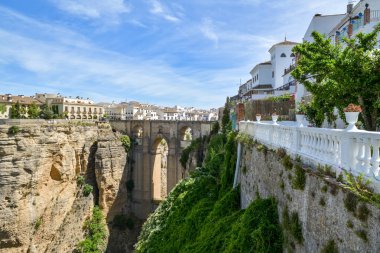 Ronda, İspanya - 9 Mayıs 2023 'te güneşli bir günde İspanya' nın Ronda kentindeki derin vadi üzerindeki taş köprüye bakın.