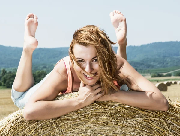 Jonge lachende vrouw poseren met de stapel van stro en genieten van — Stockfoto