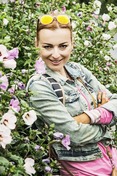 Young caucasian woman posing with hibiscus in orangery — Stock Photo, Image