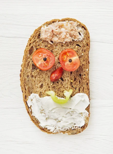 Funny face made of bread, butter, tuna, sausage, black pepper an — Stock Photo, Image