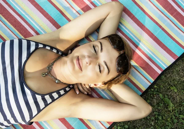 Young woman in sailor outfit is lying on the retro blanket with — Stock Photo, Image