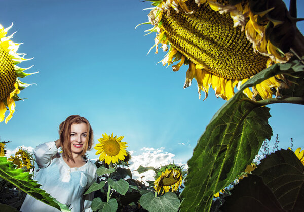 Beautiful young woman in sunflower field, seasonal natural scene