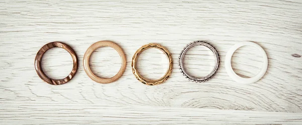 Anillos de mujer dispuestos en fila en el fondo de madera — Foto de Stock