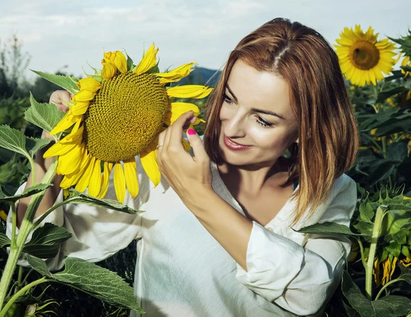 Jolie femme est debout près du tournesol et regardez-le — Photo