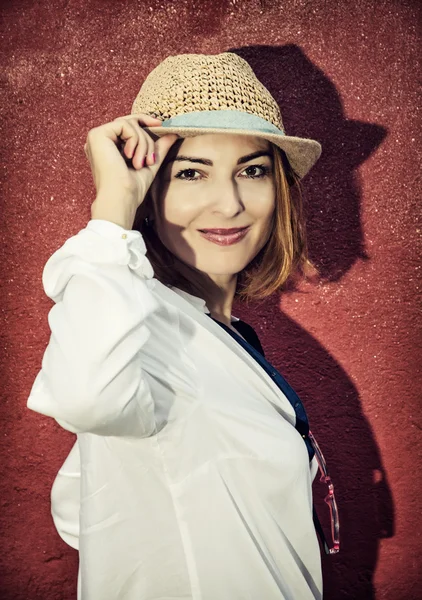 Young romantic brunette woman posing in front of the red wall — Stock Photo, Image