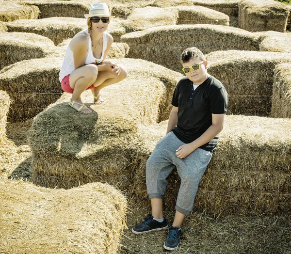 Woman with the son are sitting on the haystack — Stock Photo, Image